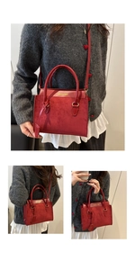 Detail view of red suede and leather crossbody bag with gold text and adjustable strap