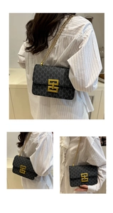 Detail of a black crossbody bag with gold M-pattern print and a metallic lock