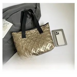 Detailed top view of a gold metallic tote bag featuring embossed bow patterns and black handles