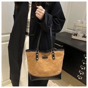 Macro detail of brown suede tote bag with quilted diamond pattern and black leather contrast
