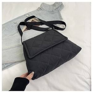 Close-up of black quilted shoulder bag featuring rhombic stitching and adjustable strap