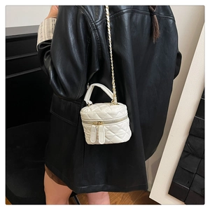 Detailed view of white quilted mini box bag with chain strap on a black leather jacket