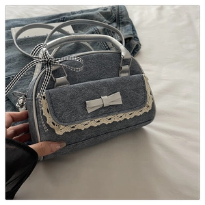 Detail of blue denim handbag featuring delicate lace trim and a grey leather bow accent