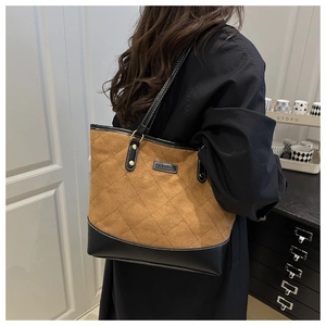 Detail of brown and black tote bag with diamond quilting and Fashion logo plate