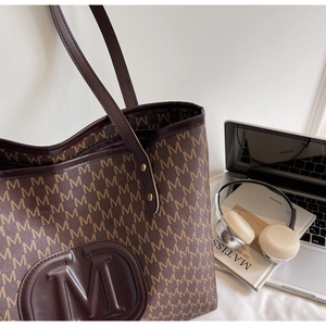 Detailed close-up of a large vintage brown tote bag with M monogram and office accessories