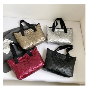 Flat lay of metallic quilted tote bags in gold, silver, burgundy, and black finishes