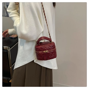 Close-up of burgundy quilted chain bag with gold-tone hardware on a fashion model