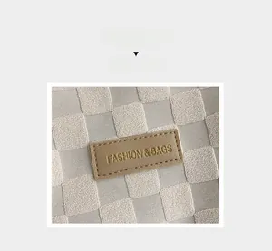 Detail of checkered towel fabric tote with a brown leather logo patch embossed with text