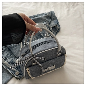 Detail of denim handbag with lace trim, bow accents and metallic zippers in Y2K style
