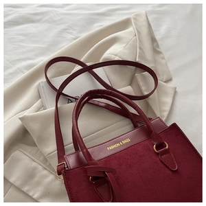 Détail d'un sac à main bordeaux avec empiècements en daim et ferrures en métal doré