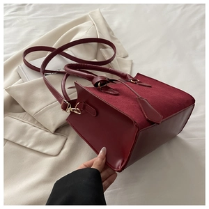 Détail des coutures en cuir bordeaux et suède avec garnitures dorées sur le sac à main