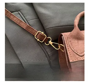Close-up of golden hardware hook and suede texture on a brown minimalist crossbody bag