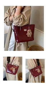 Detail of burgundy patent leather tote with metal plate and plush bear charm
