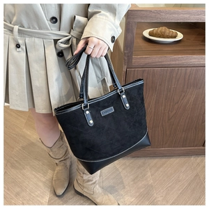 Close-up of black quilted tote bag featuring matte suede texture and metal FASHION emblem