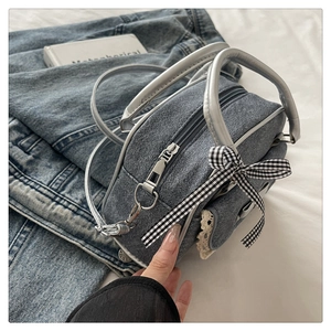 Detail of light blue denim handbag with checkered bow, lace trim and silver handle