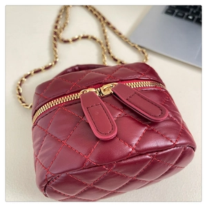 Detailed view of burgundy quilted leather box bag with gold double zippers and chain strap