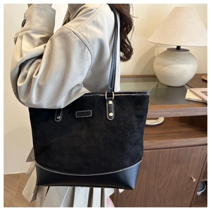 Detail of contrast stitching and mixed textures on black fashion tote bag