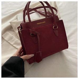 Détail du sac bandoulière bordeaux avec texte doré et texture en cuir suédé élégant