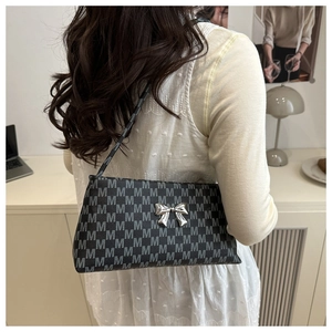 Detail view of the silver metal bow and white M-monogram print on this black shoulder bag