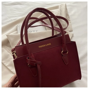 Détail du sac à main bordeaux avec textures mixtes et lettrage doré élégant