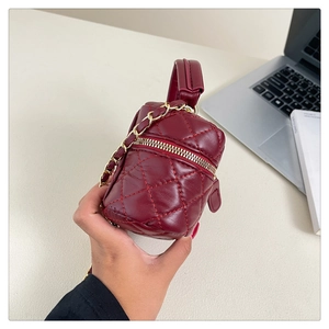 Detail view of burgundy quilted leather vanity case with gold chain strap on desktop