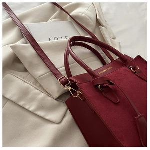 Détail du sac à main bordeaux avec lettrage et ferrures métalliques de couleur dorée
