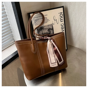 Close-up of brown tote bag featuring white contrast stitching and a decorative silk scarf