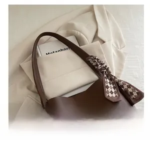 Detail of soft dark brown leather tote handle featuring a silk scarf accessory