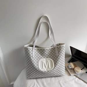 Minimalist white tote bag with M-letter print shown with a laptop and headphones