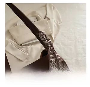 Detail of dark brown leather tote bag with a checkered silk scarf wrapped on the strap