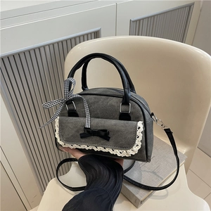 Gray denim handbag with white lace trim and black bows shown in a home setting