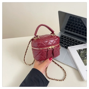 Detail of burgundy quilted mini vanity bag with golden chain strap and top handle