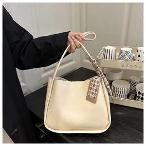 Detail of soft cream leather bucket bag with decorative patterned silk scarf handle wrap