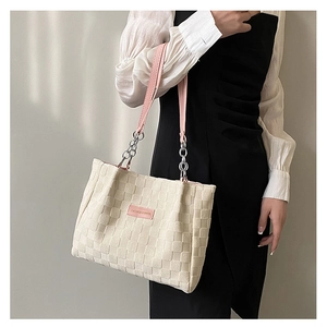 Detailed shot of cream woven tote with pink leather patch and metallic chain strap