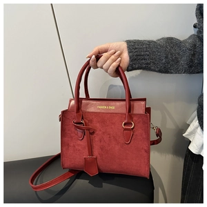 Macro view of burgundy suede and smooth leather texture on an elegant shoulder bag