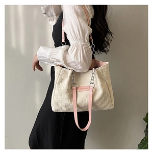 Detail of white woven tote bag featuring pink straps and silver chain link accents