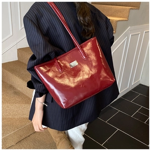 Détail du sac cabas en cuir verni bordeaux avec finition brillante et boucle argentée