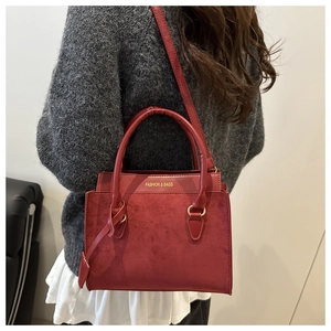 Detail of burgundy suede tote bag showing gold accents and stylish fashion logo print