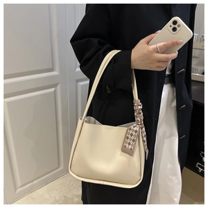 Detail of soft cream leather tote bag with a stylish brown checkered ribbon handle charm