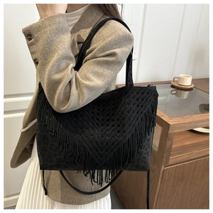 Detail of bohemian tassel fringes and leopard print texture on black tote bag