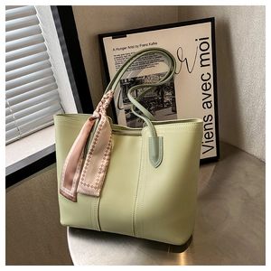 Close-up of light green tote bag with plaid silk scarf detail on metal table