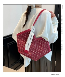Close-up of red tweed tote bag with leather handles and white logo canvas strap