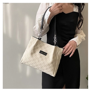 Detail of cream tote bag with checkered texture and fashion label on model
