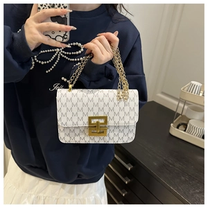 Detail of monogram printed crossbody bag featuring a golden geometric lock and chain strap