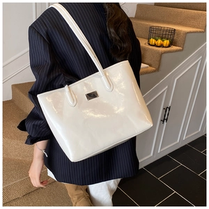 Vue de côté d'un grand sac cabas en cuir verni blanc porté par un mannequin à l'épaule