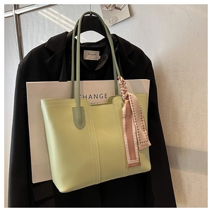 Detail of pistachio green tote bag with decorative scarf hanging on a garment rack