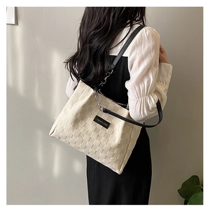 Detail of off-white woven tote bag featuring silver chain strap and fashion label
