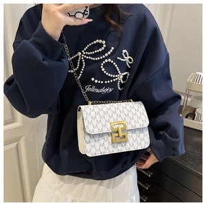 White crossbody bag with grey M-print, gold buckle, and chain strap worn by a model