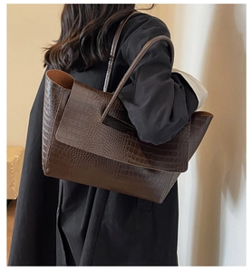 Dettaglio della borsa tote marrone caffè con stampa coccodrillo indossata da una modella
