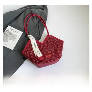 Red tweed tote bag with bow detail and shoulder strap shown in a lifestyle flat lay